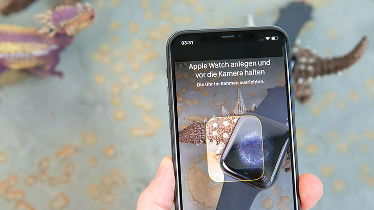 Ein iPhone wird über eine Apple Watch gehalten, um diese einzurichten.