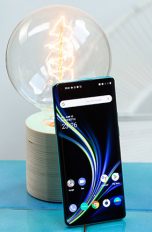 OnePlus 8 Pro Das OnePlus 8 Pro steht aufrecht angelehnt an eine Glühbirne. Das Display ist aktiviert und zeigt den Home-Bildschirm.