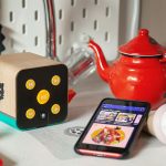 Ein Smartphone mit ge&ouml;ffneter Spotify-App und ein kindgerechter Lautsprecher in einer Spielk&uuml;che.