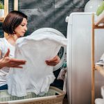 Eine Person holt ein wei&szlig;es Kleidungsst&uuml;ck aus einem Trockner.