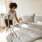 Eine Person macht ihr Bett. Die Bett&auml;sche ist Grau-Wei&szlig;.
