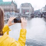 Eine Person h&auml;lt ihre Smartphone-Kamera auf Geb&auml;ude an der kleinen Alster in Hamburg.