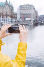 Google Lens Eine Person hält ihre Smartphone-Kamera auf Gebäude an der kleinen Alster in Hamburg.