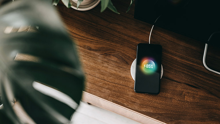 Ein Smartphone liegt auf einer Ladestation und lädt per Induktion auf.