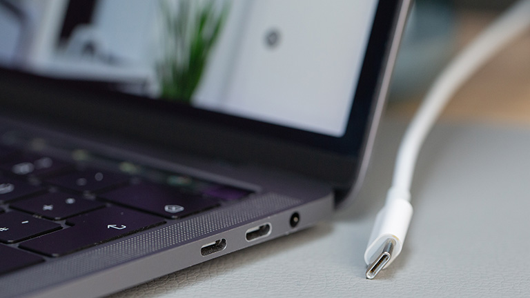 Ein Laptop mit USB-C-Buchse. Daneben ein USB-C-Kabel.