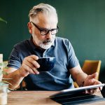 Eine Person sitzt in einem Caf&eacute; und bedient ihr iPad.