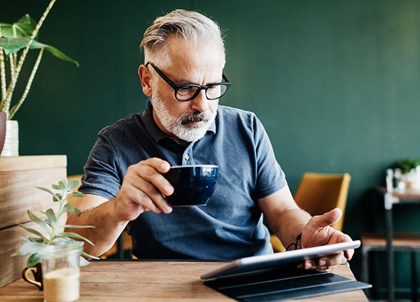Eine Person sitzt in einem Caf&eacute; und bedient ihr iPad.