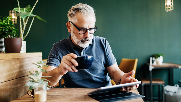 Eine Person sitzt in einem Café und bedient ihr iPad.