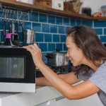Eine Person &ouml;ffnet die Mikrowelle und schaut hinein.