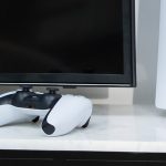 Ein DualSense-Controller neben einer PS5-Konsole.