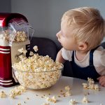 Ein Kind schaut zu, wie eine Popcornmaschine arbeitet.