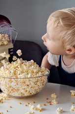 Ein Kind schaut zu, wie eine Popcornmaschine arbeitet.