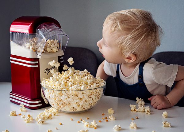 Ein Kind schaut zu, wie eine Popcornmaschine arbeitet.