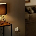 Ein Apple HomePod Mini auf einem Tisch. Daneben steht eine Lampe, die &uuml;ber eine Eve Energy mit dem Strom verbunden ist.