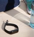 Das Fitness-Armband Mi Smart Band 5 von Xiaomi liegt auf einem hellen Holztisch. Ringsherum befinden sich Sportutensilien.