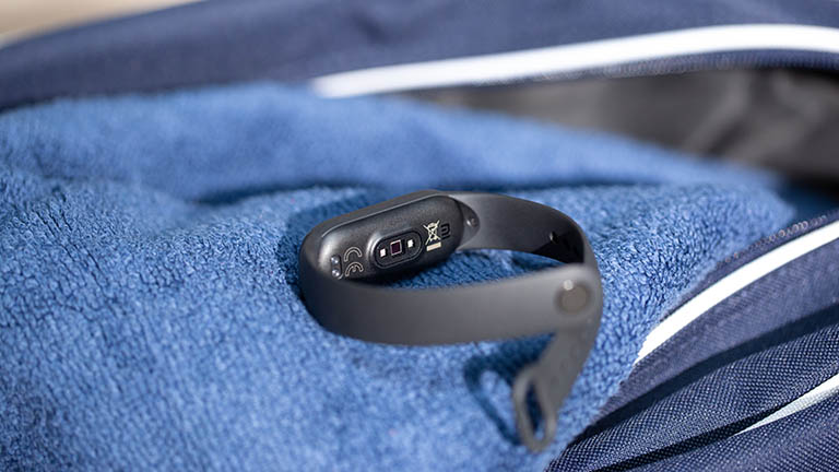 Das Xiaomi Mi Smart Band 5 liegt auf einem blauen Handtuch. Zu erkennen ist die Unterseite des Armbands und der darin verbaute Sensor für die Herzfrequenzüberwachung.