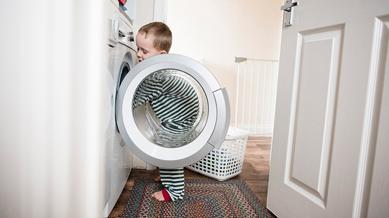 Ein Kind steht vor einer geöffneten Waschmaschine.
