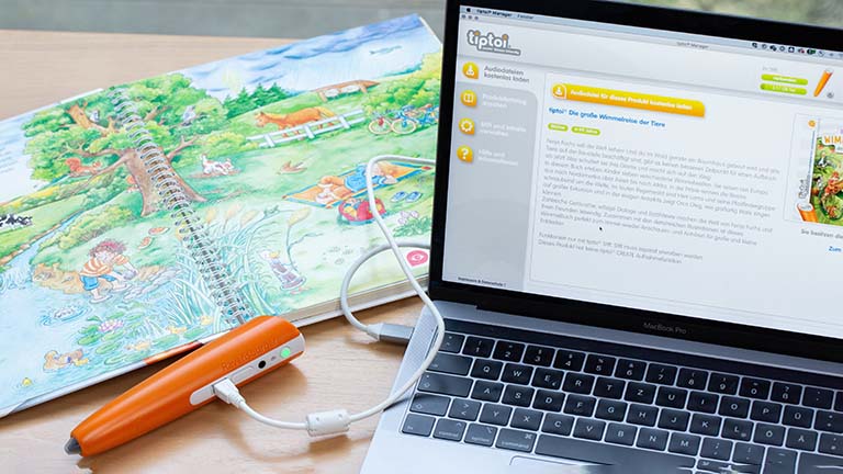 Der Tiptoi-Stift ist über ein USB-Kabel mit einem Laptop verbunden, auf dem der Tiptoi-Manager geöffnet ist.