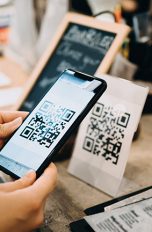 QR Code Eine Person hält ihr Smartphone auf einen QR-Code, um ihn mit der Kamera auszulesen.