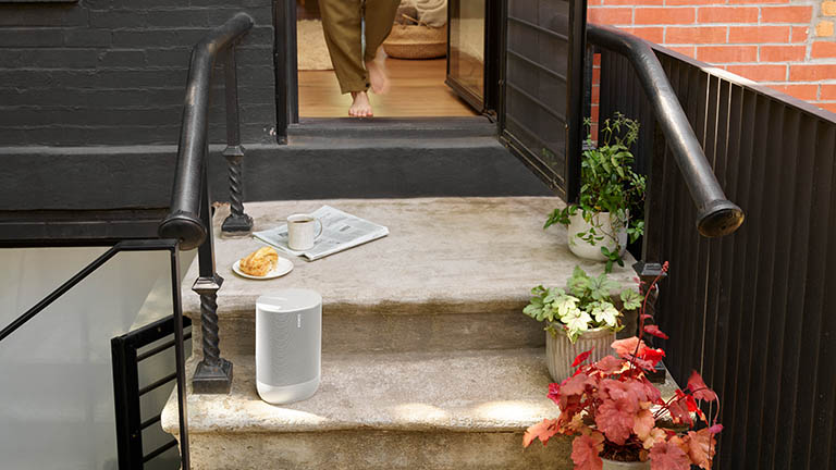Ein Sonos Move in Weiß steht auf Treppenstufen vor einem Haus.