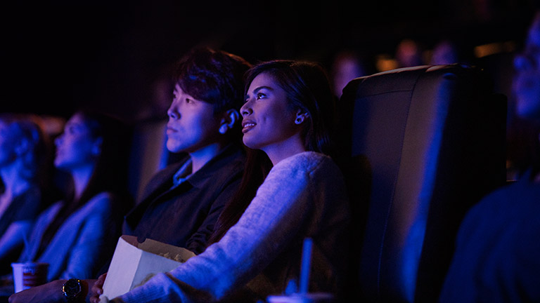 Zwei Personen sitzen in einem Kino und schauen einen Film.