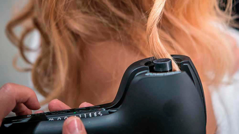 Babyliss Miracurl Eine Person hält den Babyliss Miracurl Lockenstab in den Händen und zieht eine Haarsträhne in das Gerät.