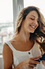 Eine Person steht im Badezimmer und b&uuml;rstet sich die langen Haare.