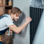 Eine Person verschiebt einen K&uuml;hlschrank in einer K&uuml;che.