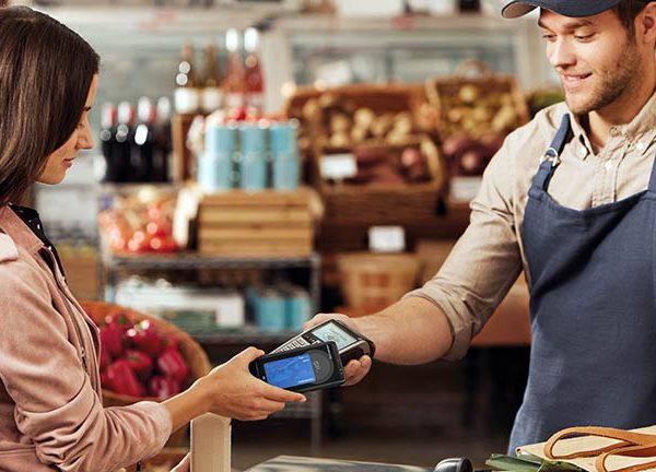 Eine Person bezahlt in einem Lebensmittelgesch&auml;ft mit dem Smartphone.