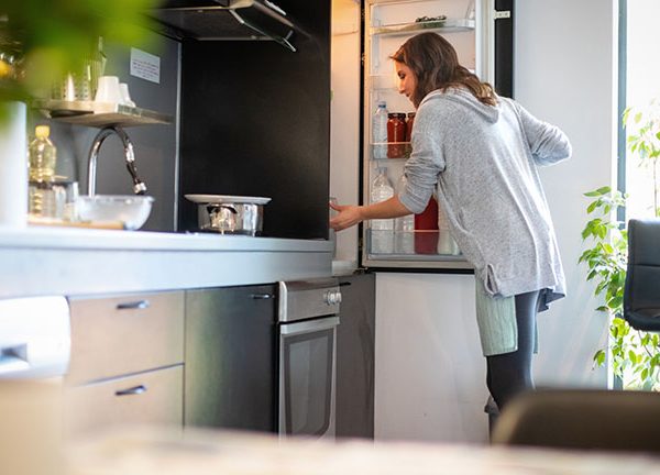 Eine Person &ouml;ffnet den K&uuml;hlschrank und schaut hinein.