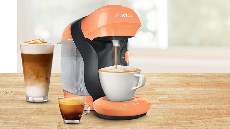 Ein Bosch Tassimo in Orange, aus der gerade frischer Kaffee in eine Tasse fließt.