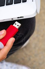 Eine Person ist dabei, einen USB-Stick in einen Laptop zu stecken.