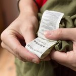 Eine Person schaut auf den eingen&auml;hten Zettel mit den Pflegehinweisen.