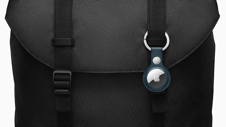 Ein schwarzer Rucksack, an dem ein Apple AirTag mithilfe eines farblich passenden Schlüsselanhängers befestigt ist.