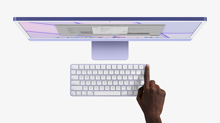 Eine Person hält ihren Finger auf die Touch-ID-Fläche auf dem Magic Keyboard in Violett.