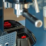 Nahaufnahme einer Smeg-Espressomaschine mit zwei Gläsern Latte Macchiato daneben.