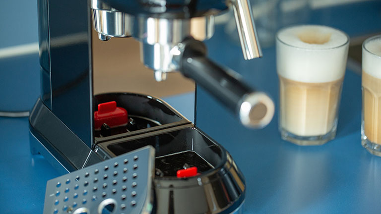 Nahaufnahme einer Smeg-Espressomaschine mit zwei Gläsern Latte Macchiato daneben.