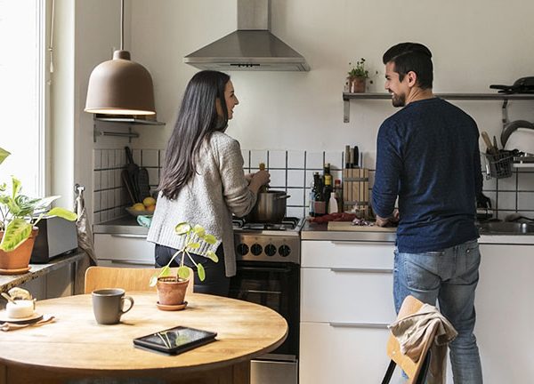 Zwei Personen stehen in einer kleinen Wohnk&uuml;che und kochen zusammen.