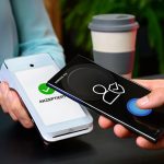 Ein Smartphone wird an ein Kartenleseger&auml;t f&uuml;r einen kontaktlosen Bezahlvorgang gehalten.