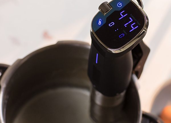 Ein Sous-vide-Stick steckt in einem Topf mit Wasser, das Display zeigt 47,4 Grad Celsius an.