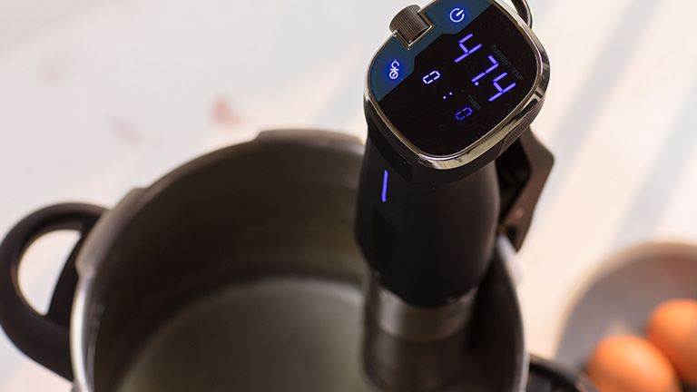 Ein Sous-vide-Stick steckt in einem Topf mit Wasser, das Display zeigt 47,4 Grad Celsius an.