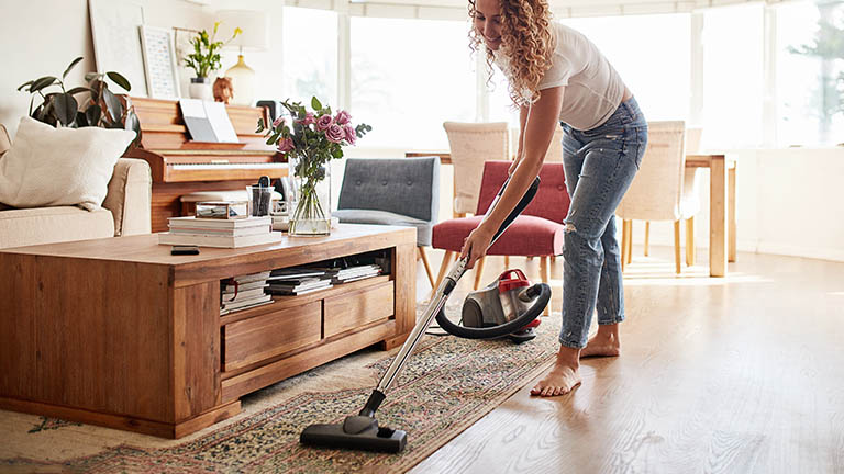Eine Person saugt mit einem beutellosen Sauger &uuml;ber einen orientalischen Teppich.