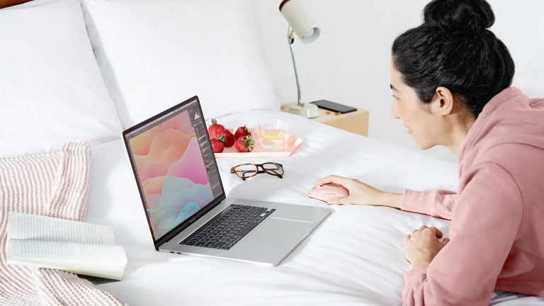 Eine Person nutzt eine Logitech MX Anywhere 3 an einem Laptop auf dem Bett.