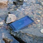 Ein Smartphone liegt in einem Bach. Es ist von Wasser bedeckt.