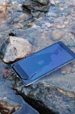 Ein Smartphone liegt in einem Bach. Es ist von Wasser bedeckt.