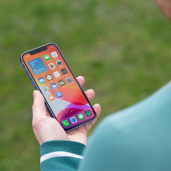 Eine Person h&auml;lt ein iPhone 12 in der Hand und blickt darauf.
