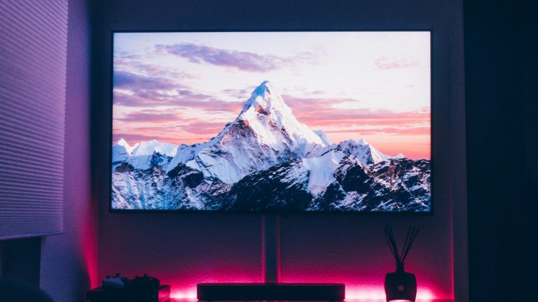 Blick auf einen großen Fernseher in einer Wohnung, auf dem ein schneebedeckter Berg zu sehen ist.