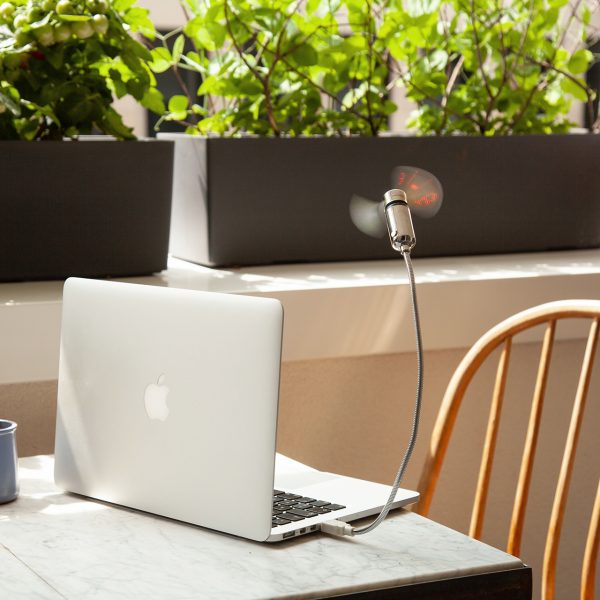 Der Hama USB-Ventilator an einem MacBook, das auf einem Tisch auf einem Balkon steht.