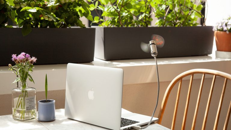 Der Hama USB-Ventilator an einem MacBook, das auf einem Tisch auf einem Balkon steht.
