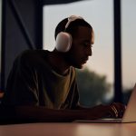 Eine Person mit Apple AirPods Max sitzt vor einem MacBook.